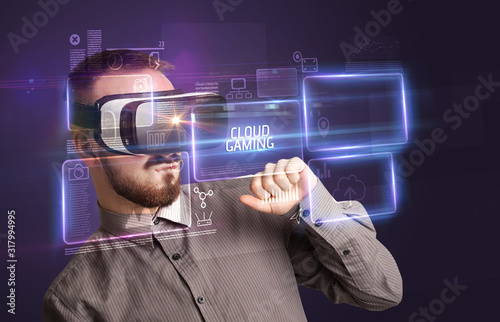 Businessman looking through Virtual Reality glasses with CLOUD GAMING inscription, new technology concept