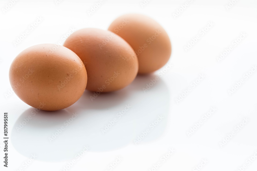Three large raw brown chicken eggs lie nearby on a white background. Copyspace
