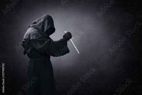 Fototapeta Hooded man with dagger in the dark
