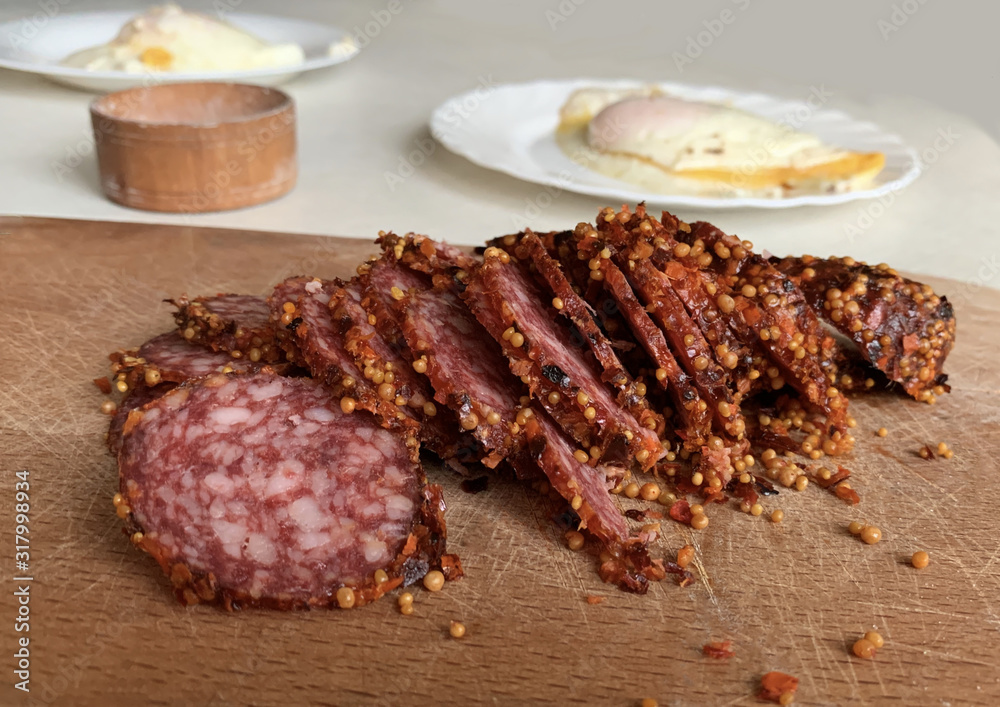 Raw smoked sausage with spices on the table. Sliced smoked sausage on a cutting board. Meat sausages for breakfast. Raw smoked sausage with spices on the table. Sliced smoked sausage on a cutting board. Meat sausages for breakfast.