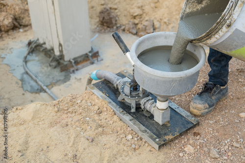 Specialist using machine grout pressure pump for grouting non-shrink concrete to precast column photo