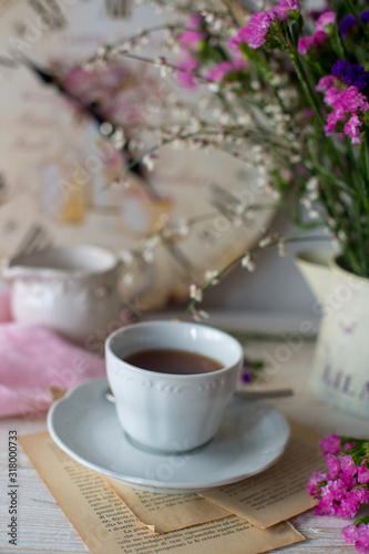 Tazza di tè con sullo sfondo vaso di fiori e orologio