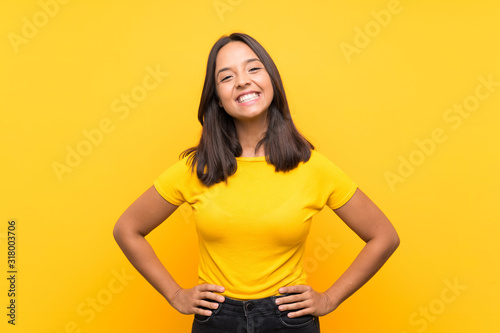 Young brunette girl over isolated background posing with arms at hip and smiling