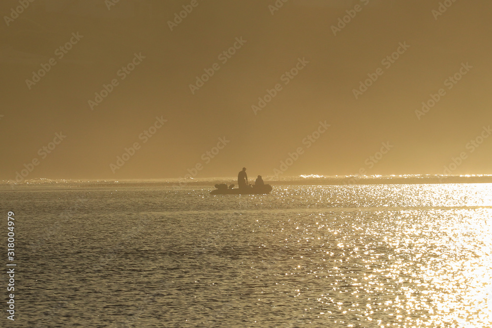 Fisherman on a boat on a lake at sunrise