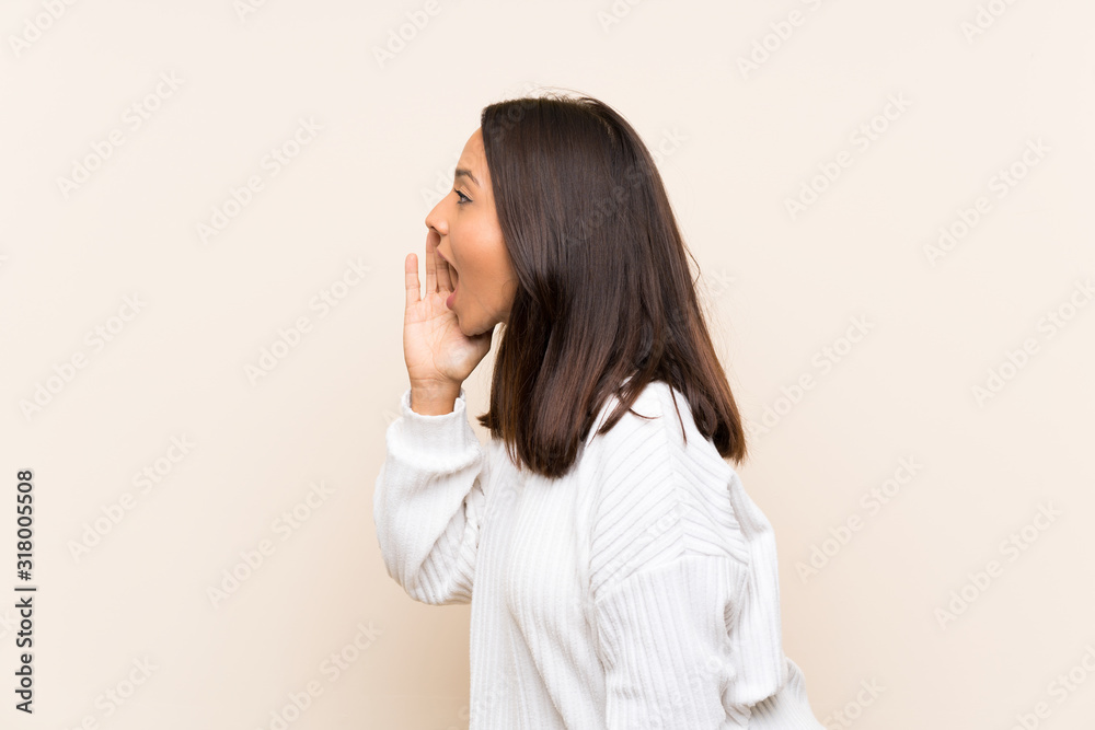 Young brunette woman with white sweater over isolated background shouting with mouth wide open Young brunette woman with white sweater over isolated background shouting with mouth wide open