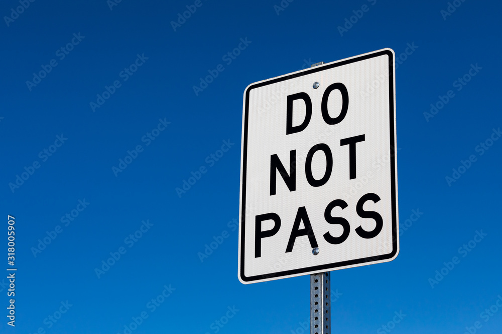 Closeup angled view of do not pass reflective sign. Isolated on deep blue sky background. Closeup angled view of do not pass reflective sign. Isolated on deep blue sky background.