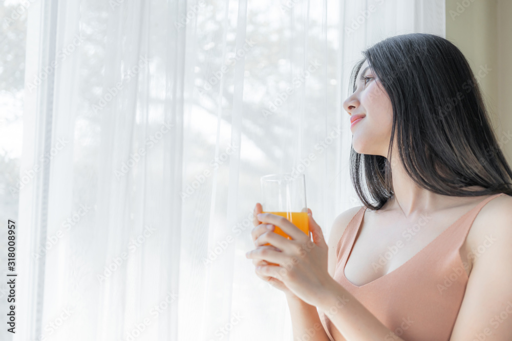 Beautiful beauty woman Asian cute girl feel happy drinking orange juice for good health in the morning , enjoying time in her home white bedroom background - lifestyle beauty woman concept Beautiful beauty woman Asian cute girl feel happy drinking orange juice for good health in the morning , enjoying time in her home white bedroom background - lifestyle beauty woman concept