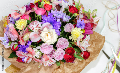 beautiful bouquet with different flowers, roses and chrysanthemums, scissors and thread