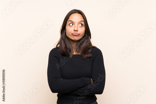 Young brunette woman with white sweater over isolated background making doubts gesture while lifting the shoulders © luismolinero