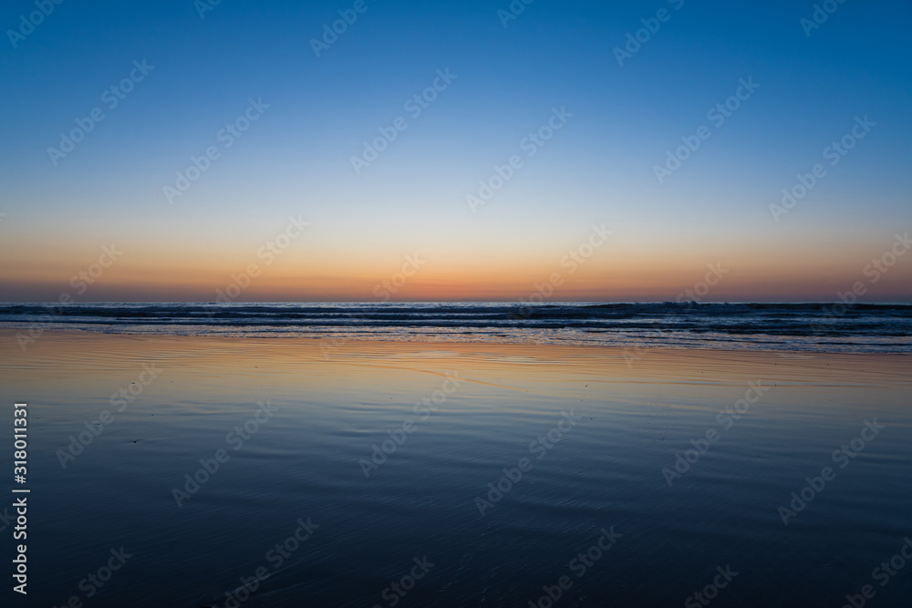 Colorful sunset reflected in a wet sandy beach