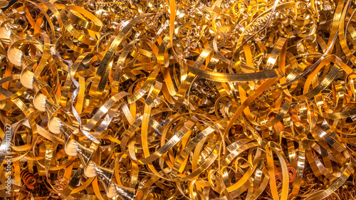 Golden background. Abstract gold background of metal shavings. Wallpaper or screensaver of yellow metallic chips. Processing of ferrous and non-ferrous metals in a factory or plant. Colored shavings.