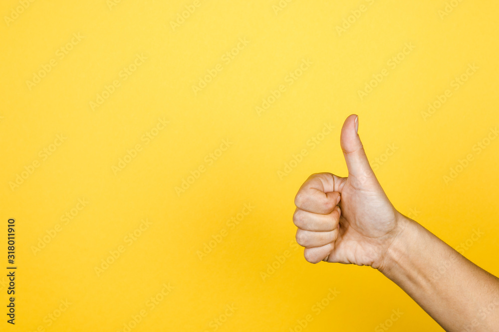 closeup of thumbs up symbol on yellow background