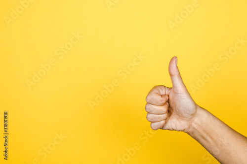 closeup of thumbs up symbol on yellow background
