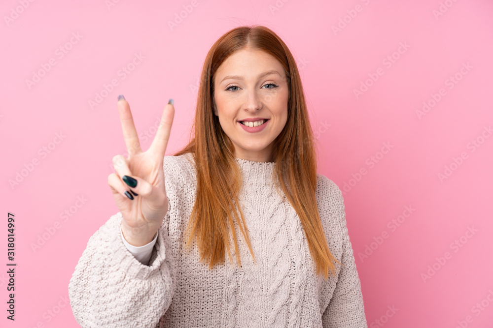 Young redhead woman over isolated pink background smiling and showing victory sign Young redhead woman over isolated pink background smiling and showing victory sign