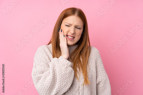 Young redhead woman over isolated pink background with toothache