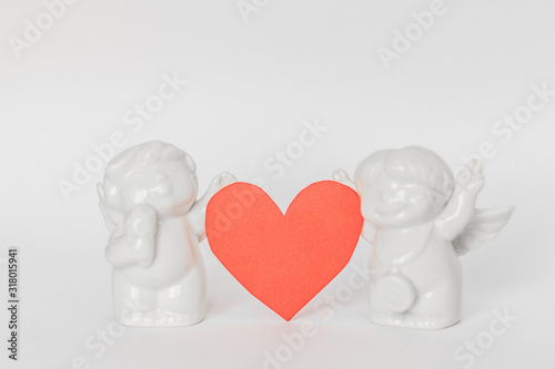 Ceramic figurines on a white background and hearts in blur . Valentine's Day. Selective focus.