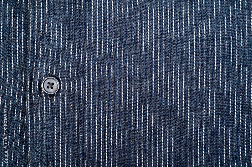 The texture of a denim shirt in dark blue with a small strip, on buttons