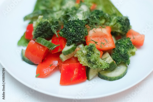 Classic vegetable salad with broccoli and tomatoes. Salad on a white plate.