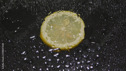 water drops over lemon slices on a black background close-up