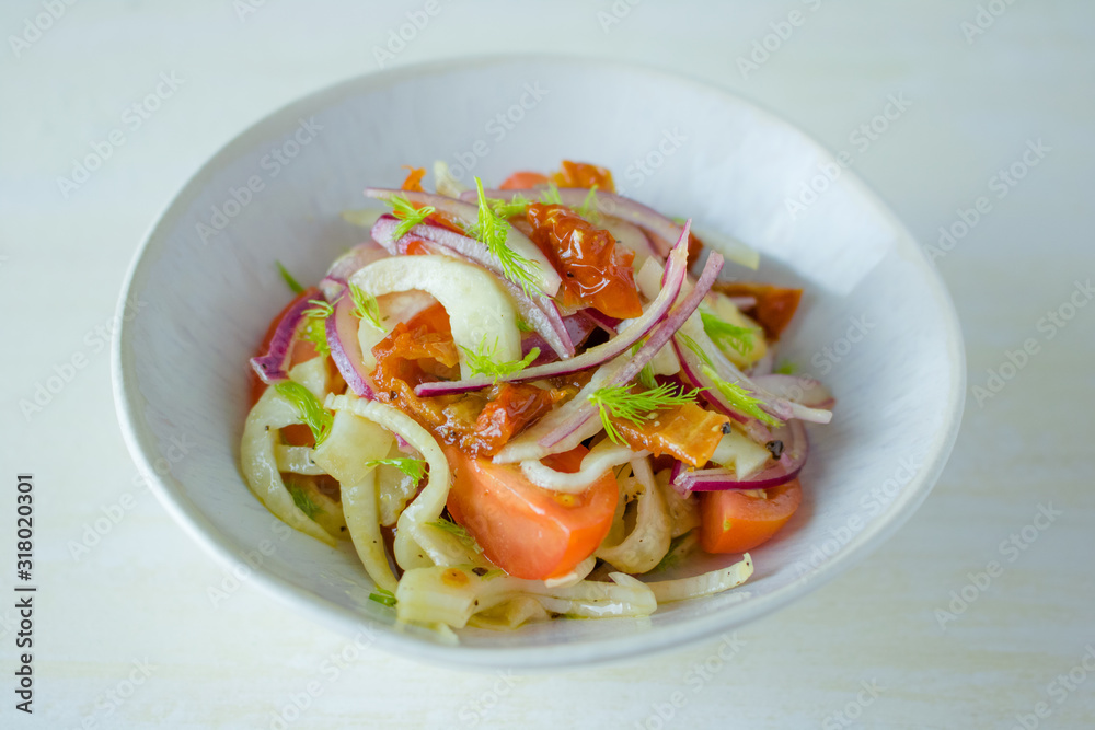 Food photography of a fennel tomato salad in a ceramic bowl on a white background. Food photography of a fennel tomato salad in a ceramic bowl on a white background.