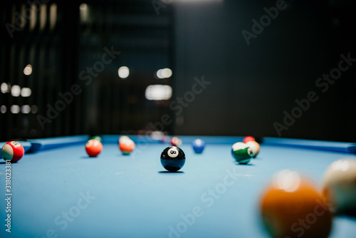 Billiards balls in a blue pool table. Spots and stripes ball in triangle. Number eight in focus