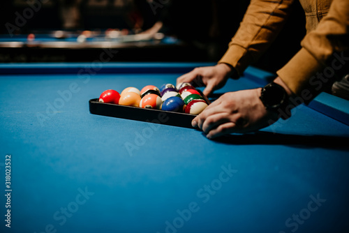 A men preparing pool balls in triangle. Blue billiard table