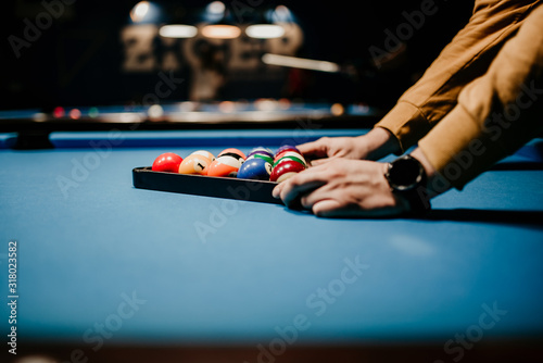 Photography A men preparing pool balls in triangle. Blue billiard table