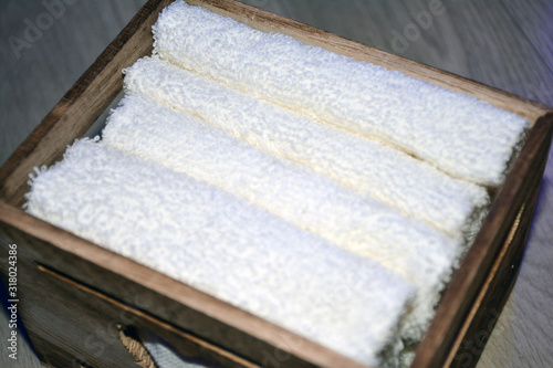 Wooden box for white towels. Face towel. Skin care. White towels in a wooden box on a brown background.
