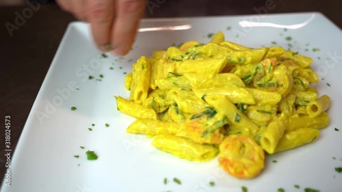 Italian cook impacts parsley around the pasta with saffron, slow motion, close up