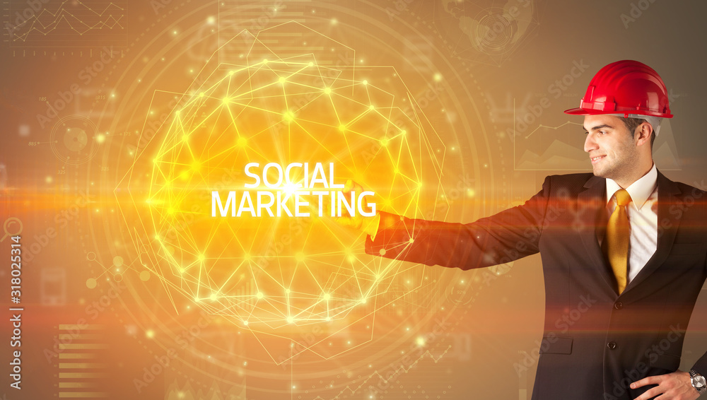 Handsome businessman with helmet drawing SOCIAL MARKETING inscription, social construction concept Handsome businessman with helmet drawing SOCIAL MARKETING inscription, social construction concept