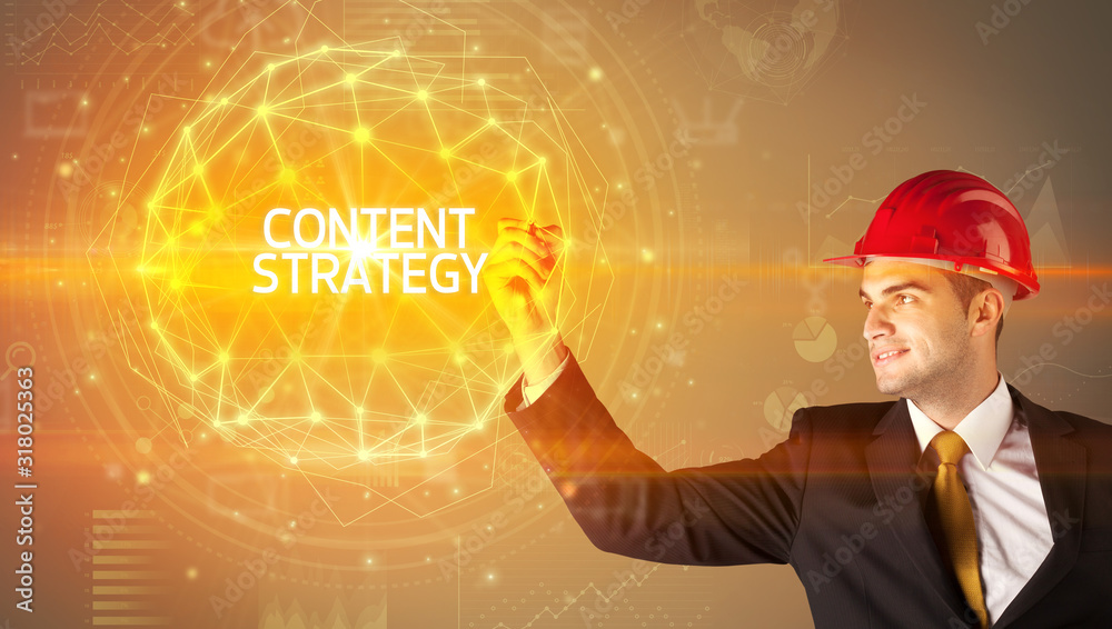 Handsome businessman with helmet drawing CONTENT STRATEGY inscription, social construction concept Handsome businessman with helmet drawing CONTENT STRATEGY inscription, social construction concept