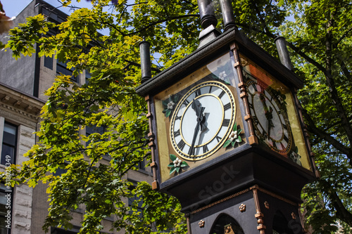 Gastown steam clock in Vancouver. Horizontal detailed close up with green leafs behind it. photo