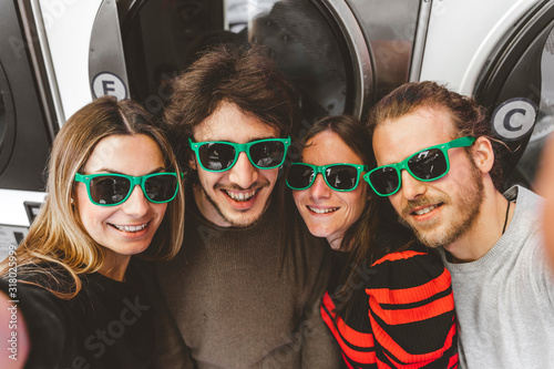 group of young friends wearing green sunglasses having fun taking a selfie