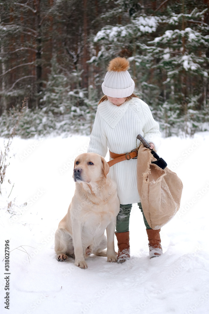 a little girl in white knitted clothes walks in the forest with her dog Labrador. looking for game or tree for home