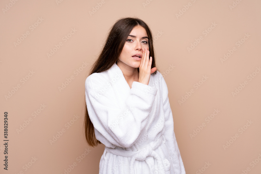 Young girl in a bathrobe over isolated background whispering something Young girl in a bathrobe over isolated background whispering something
