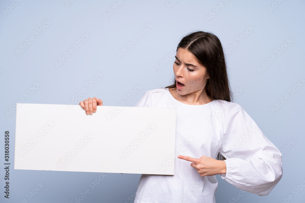 Young woman over isolated blue background holding an empty white placard for insert a concept Young woman over isolated blue background holding an empty white placard for insert a concept