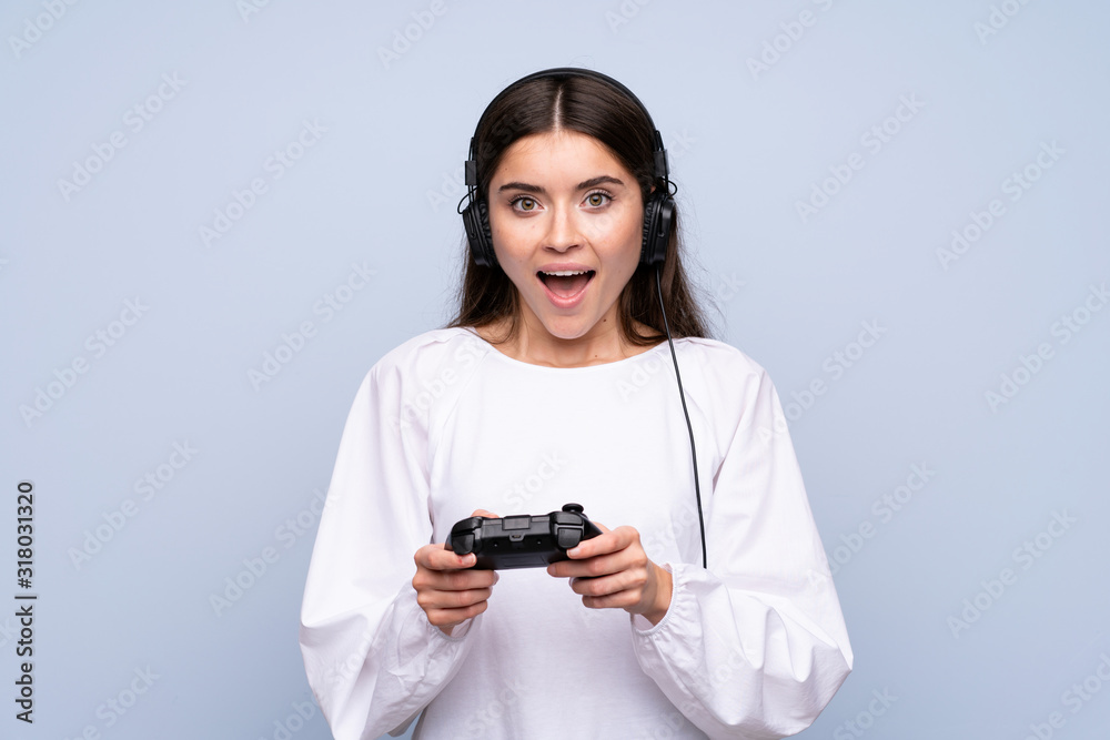 Young woman over isolated blue background playing at videogames Young woman over isolated blue background playing at videogames