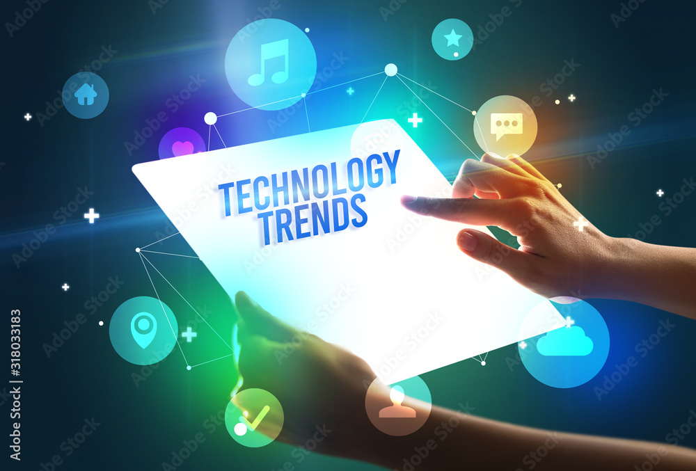 Holding futuristic tablet with TECHNOLOGY TRENDS inscription, new technology concept Holding futuristic tablet with TECHNOLOGY TRENDS inscription, new technology concept