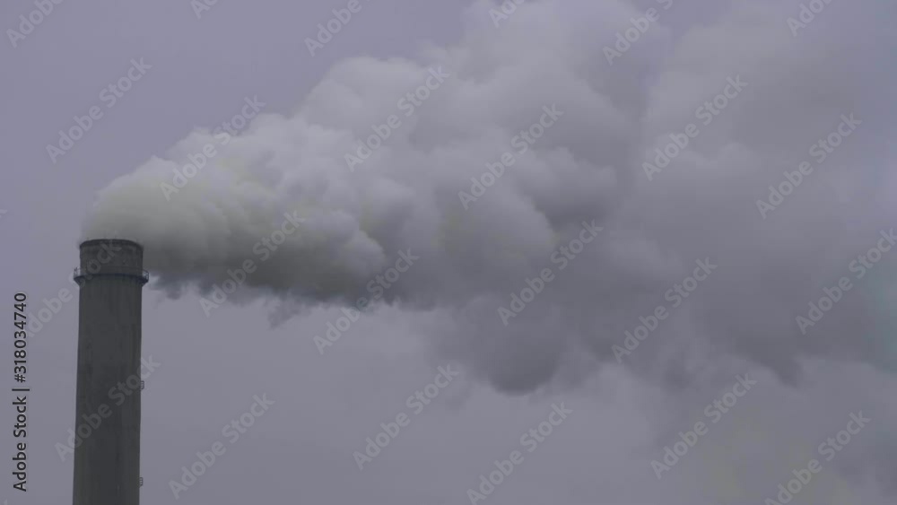 Plant with a puff of smoke. Air pollution by smoke coming out of factory chimney. Industrial smoke from chimney on blue sky Plant with a puff of smoke. Air pollution by smoke coming out of factory chimney. Industrial smoke from chimney on blue sky