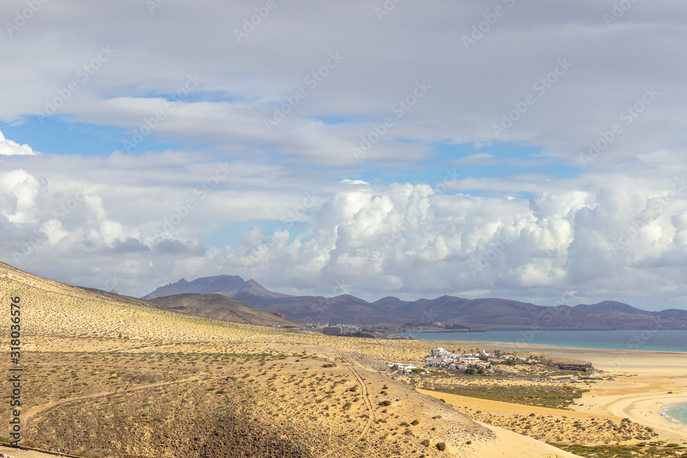 Panoramic view at sandy beach of Risco del Paso on canary island Fuerteventura with  turquoise water and mountain range in the background