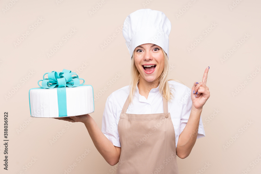 Young Russian woman with a big cake over isolated background pointing up a great idea Young Russian woman with a big cake over isolated background pointing up a great idea