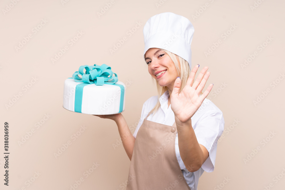 Young Russian woman with a big cake over isolated background saluting with hand with happy expression Young Russian woman with a big cake over isolated background saluting with hand with happy expression