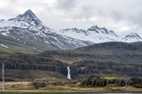 Long exposure shot by the river of Hamersa with snowy mountain peaks, basalt columns and waterfall underneath. From Hamarsdalur near Bragdavellir in east Iceland. Travel and landscape concept. photo