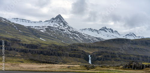 Long exposure shot by the river of Hamersa with snowy mountain peaks, basalt columns and waterfall underneath. From Hamarsdalur near Bragdavellir in east Iceland. Travel and landscape concept. photo