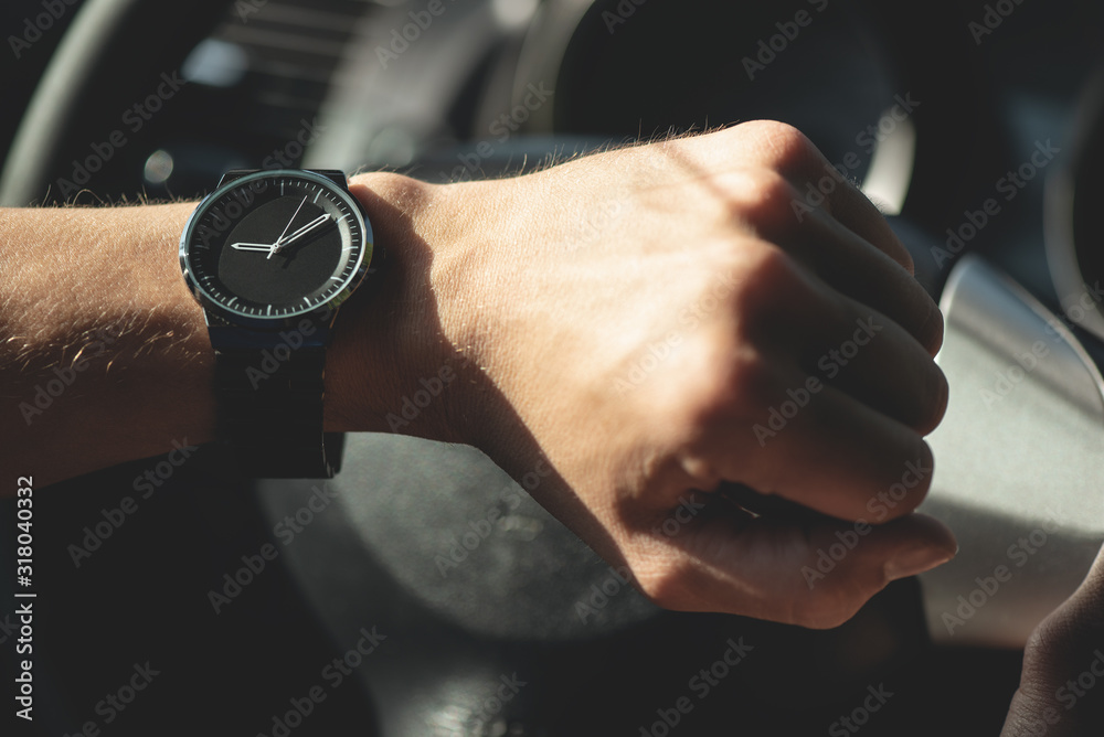 Driver is looking on his wrist watch close up.