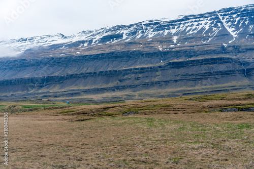 Little blue house with big snow covered mountains. From Hamarsdalur near Bragdavellir in east Iceland. Travel and landscape concept. photo