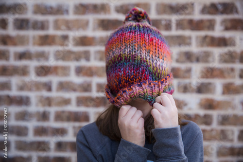 Young girl wearing winter hat over face