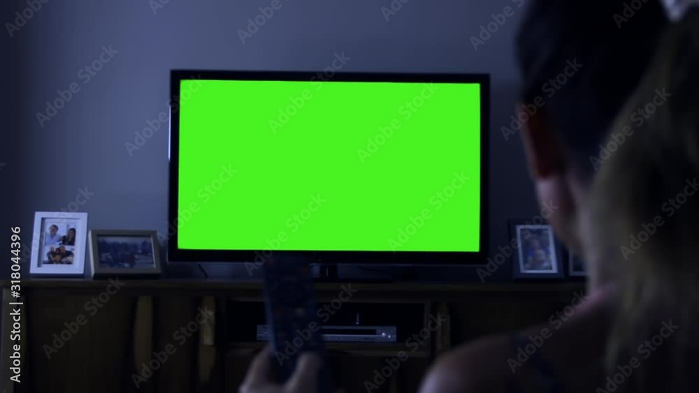 Woman Watching a TV with Green Screen at Home. Night Tone. Woman Watching a TV with Green Screen at Home. Night Tone.