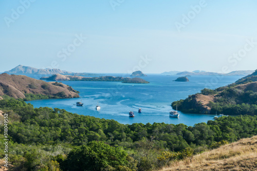 A view from top of the Komodo Island in Indonesia. Discovering new places. There is a lot of boats anchored to the shores of the island's bay. Other islands in the back. Volcanic island. photo