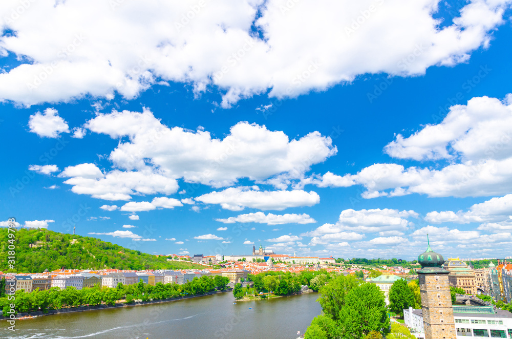 Aerial panoramic view of Prague city, historical center with Prague Castle, St. Vitus Cathedral, Hradcany district, green hills, Vltava river, blue sky white clouds background, Bohemia, Czech Republic